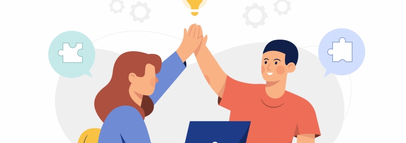 'Dwie osoby siedzące obok siebie przybijają sobie "piątkę". Na stole przed nimi stoi laptop. Fot. Freepik.com'